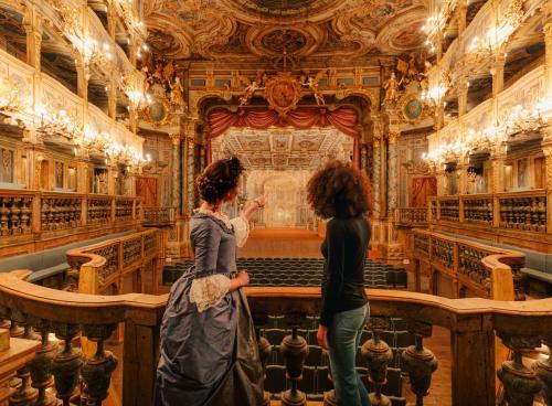 images/2021/Nov2021/12/Bayreuth_Darstellerin_zeigt_einer_Frau_das_UNESCO_Weltkulturerbe_Markgrfliches_Opernhaus.jpeg